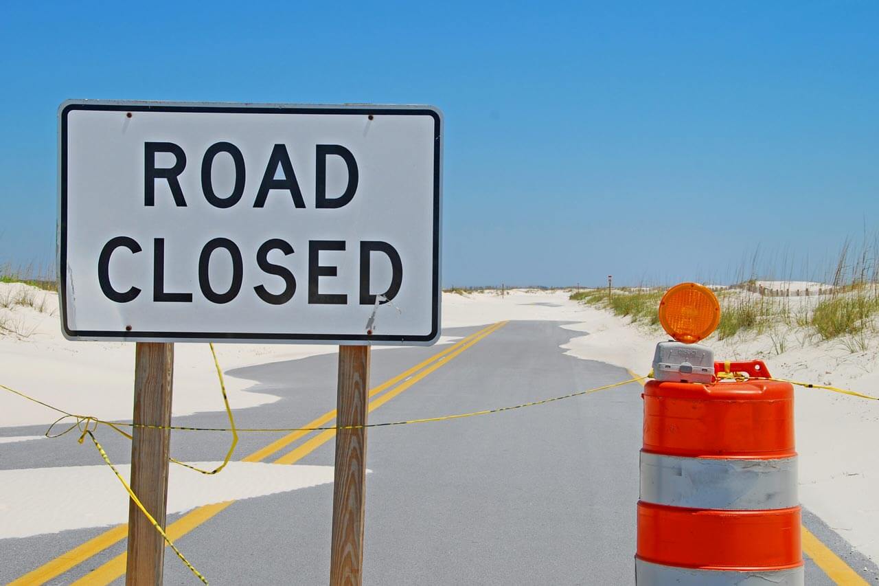 road closed sign on sandy road