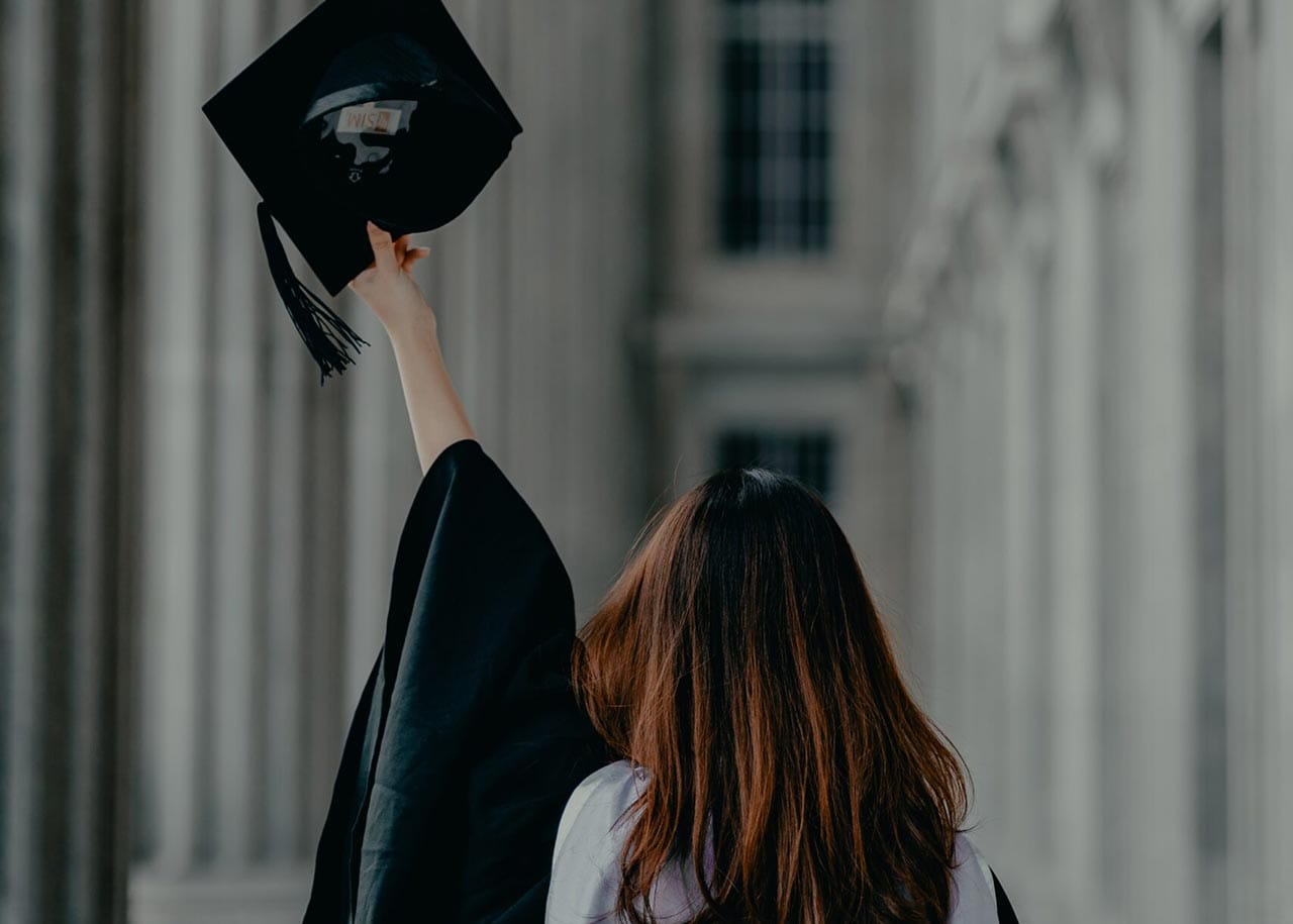 graduate throwing their graduate cap in the air in a structured building