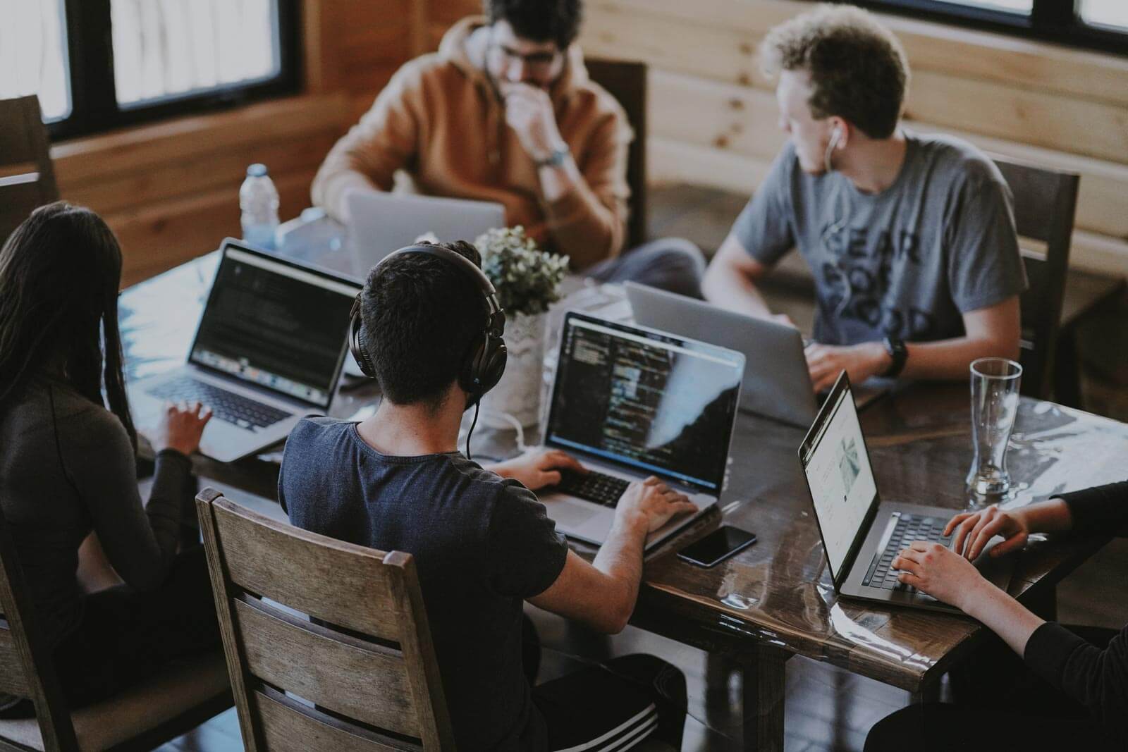 students sitting at a table with laptops open and studying