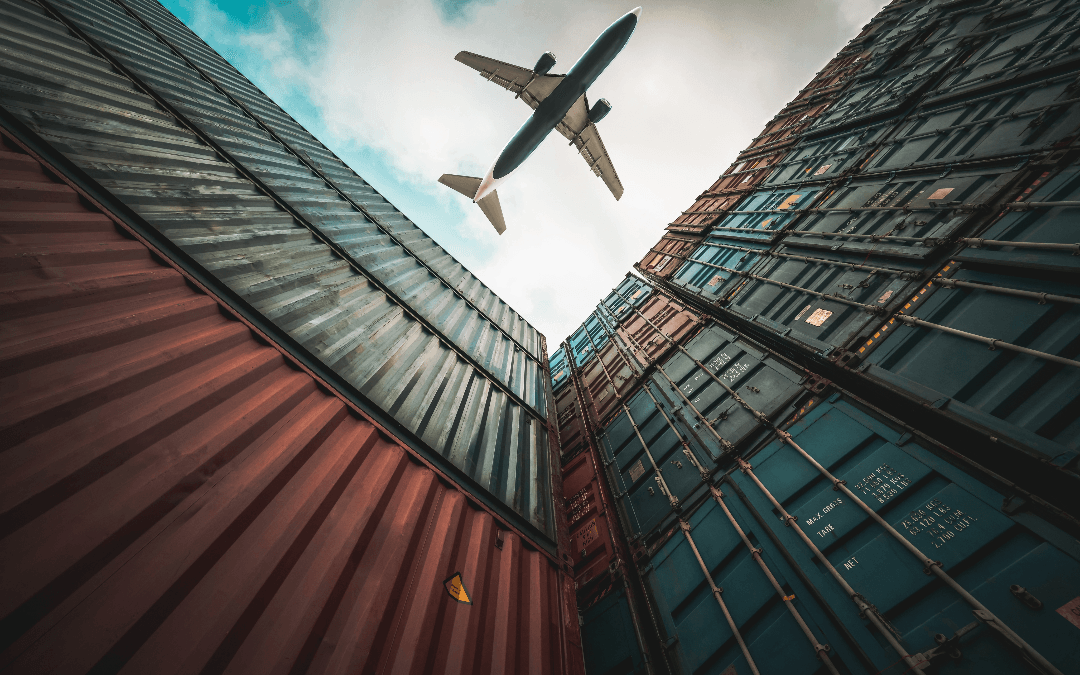 plane flying over port containers