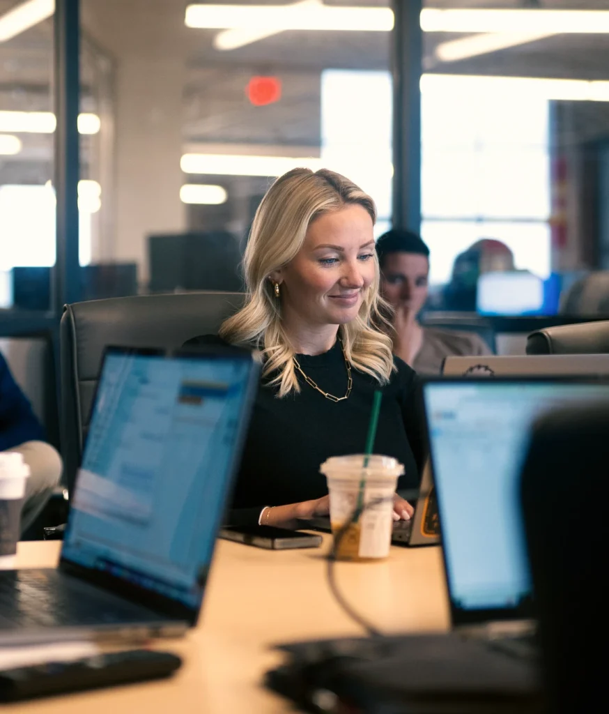 A KCH Transportation sales specialist works on her laptop with others during a meeting.