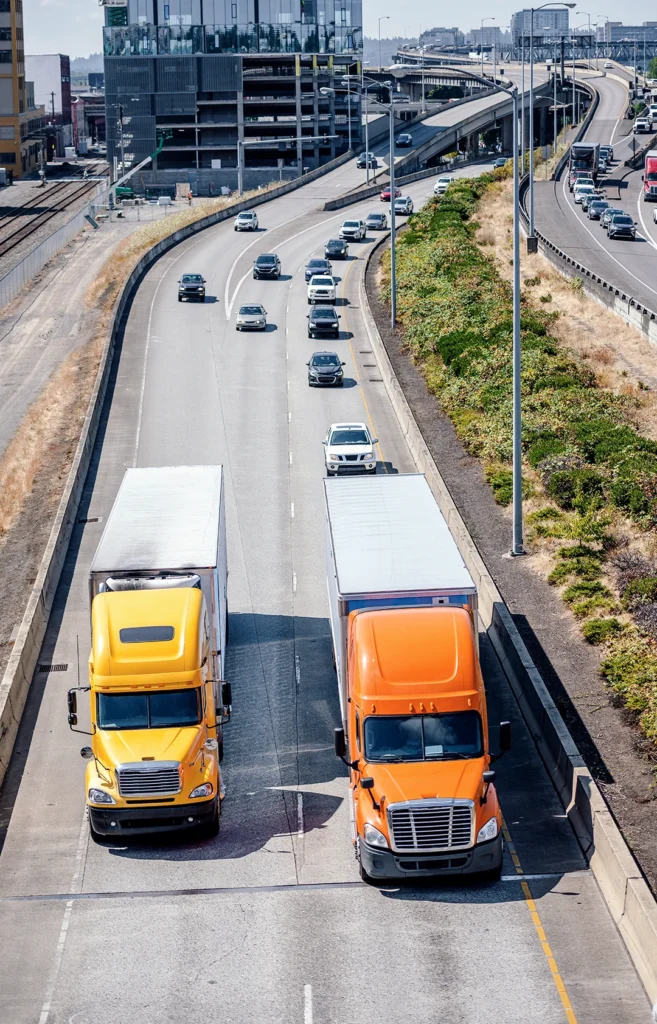 Two dry van trucks travel down the highway to deliver freight.