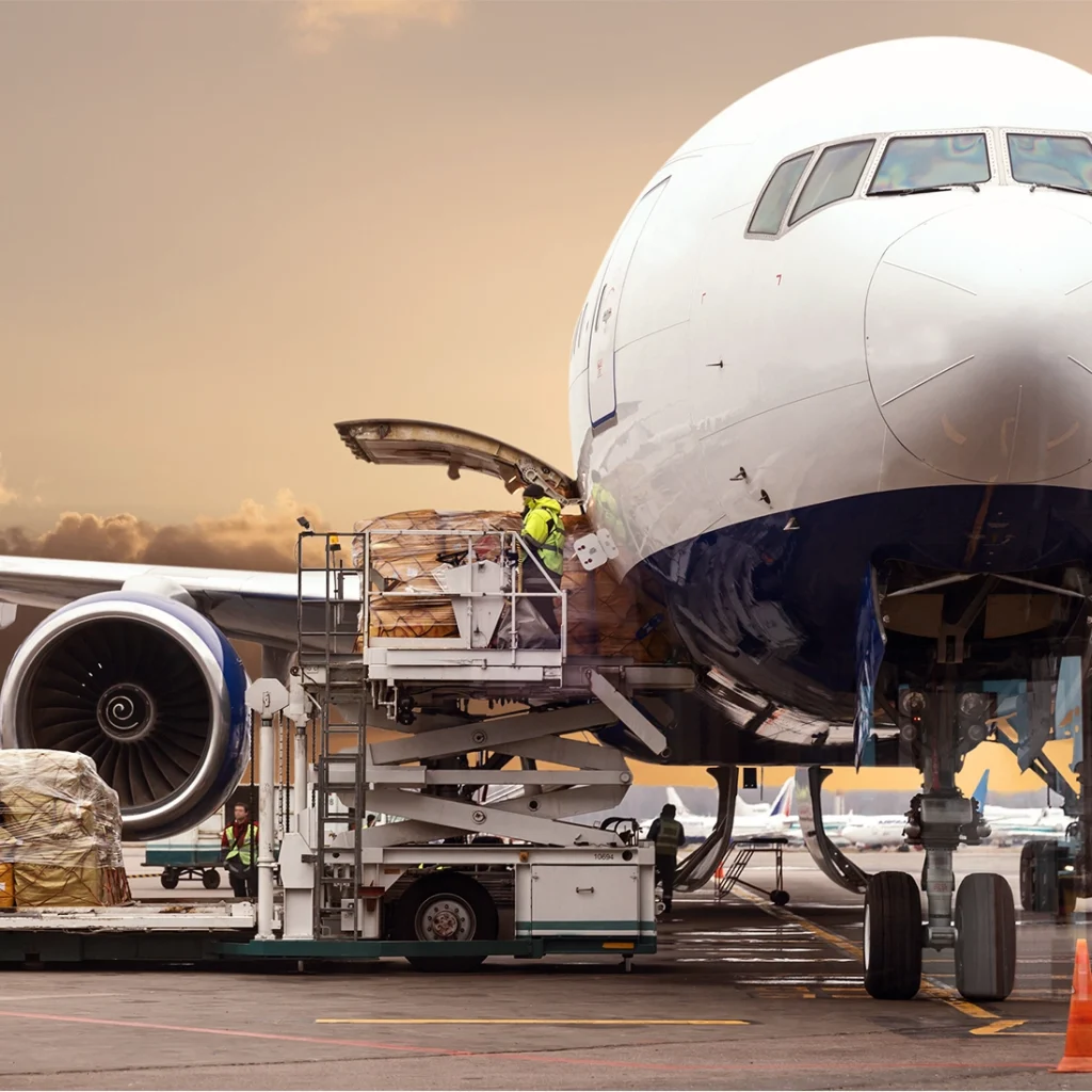 A person loading a commercial airplane with cargo.